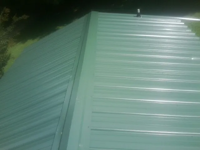 New green metal panels meeting at the ridge of a roof — Flat Roof Repair work by our crew in Searchlight