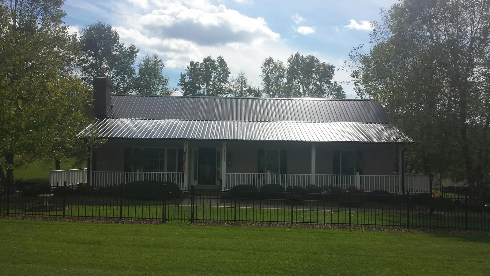 Gray metal roof on a brick ranch with a full width front porch — Gutter Guard Installation work by our crew in Searchlight