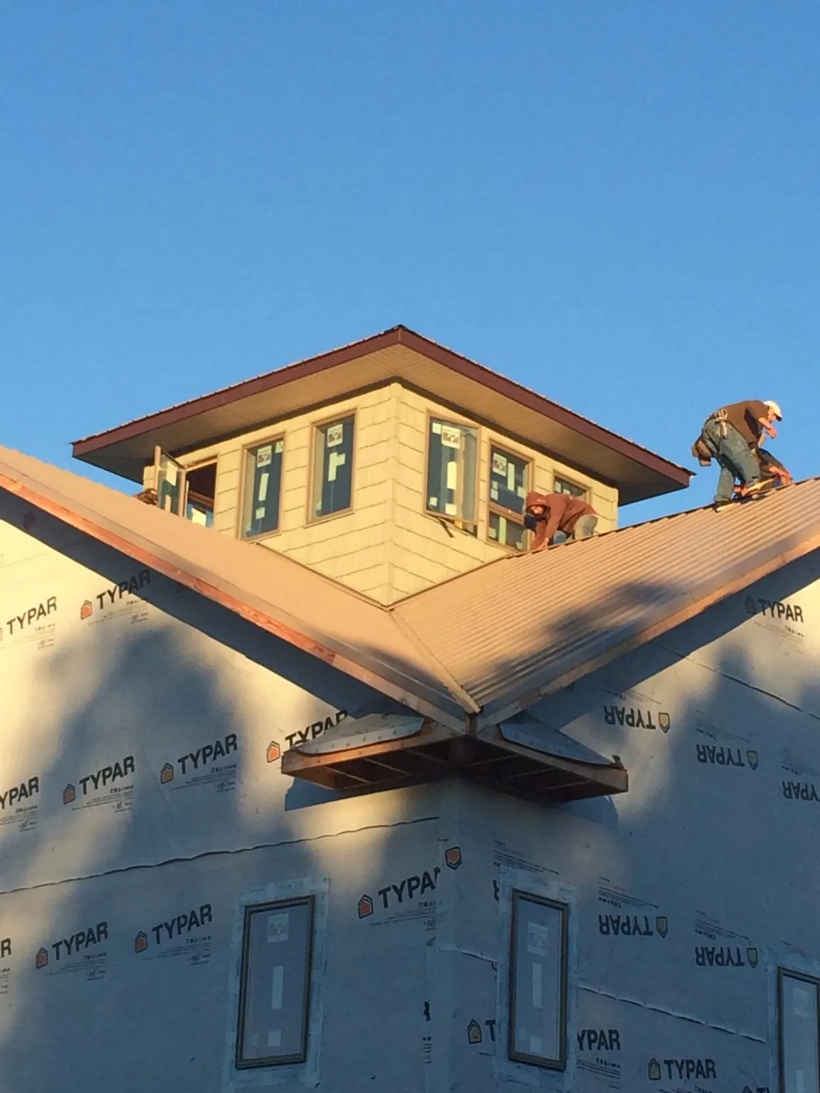 Roofers working around a rooftop cupola on a new metal roof at sunset — Roof Waterproofing in Searchlight by Roofing Brothers